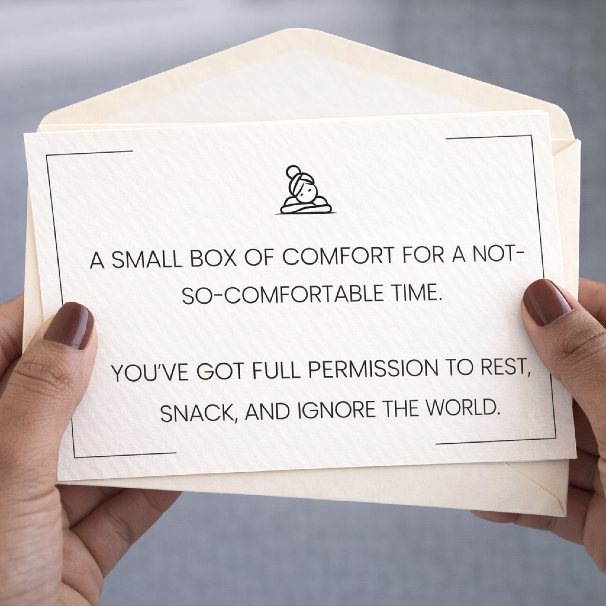Enveloped card with comfort message held by hands against a gray background