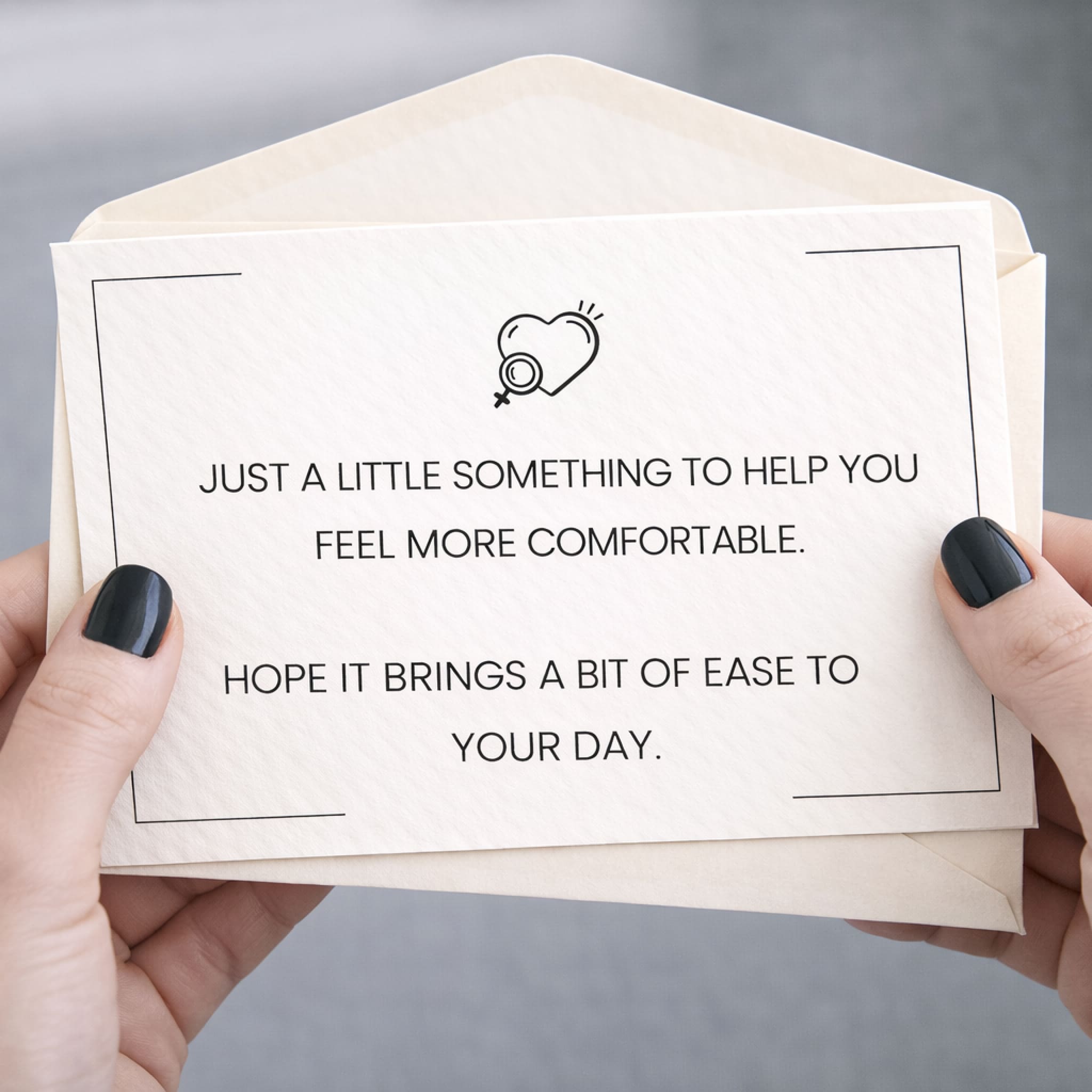 Envelope with a card inside held by hands, with text and a heart symbol.