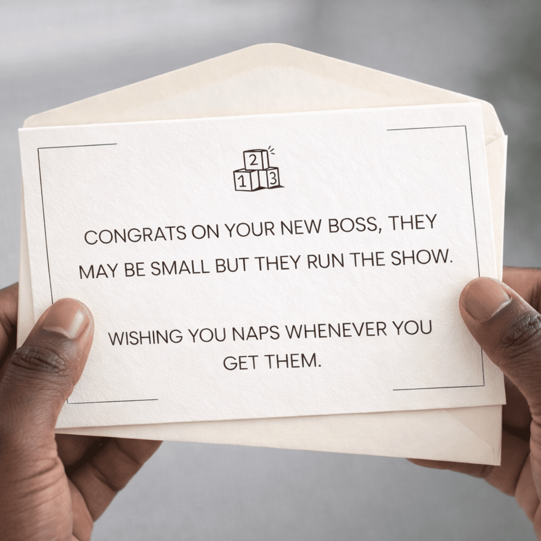 Hand holding a card with humorous text about a new boss, on a neutral background