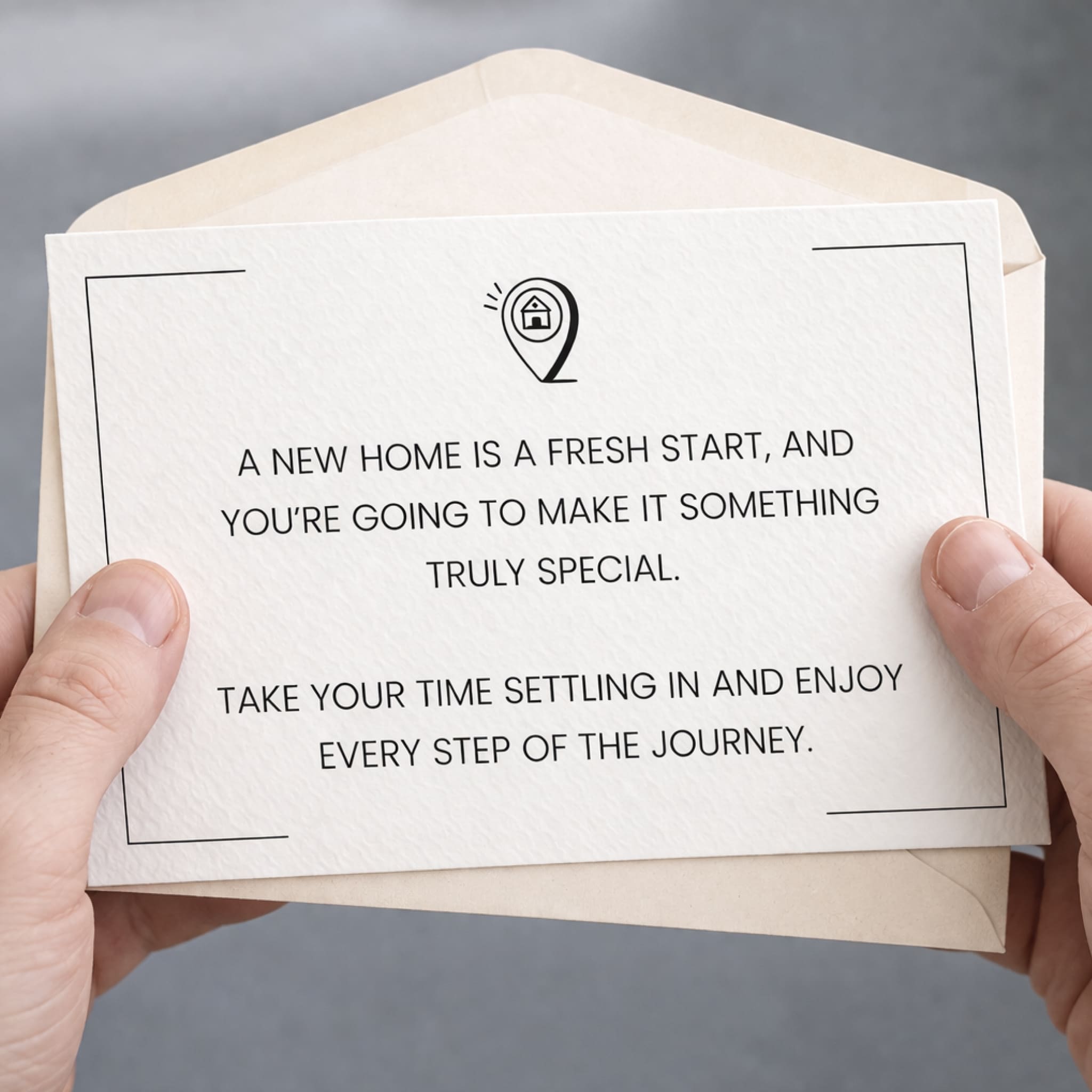Card with a message about a new home being a fresh start, held in hands against a neutral background.