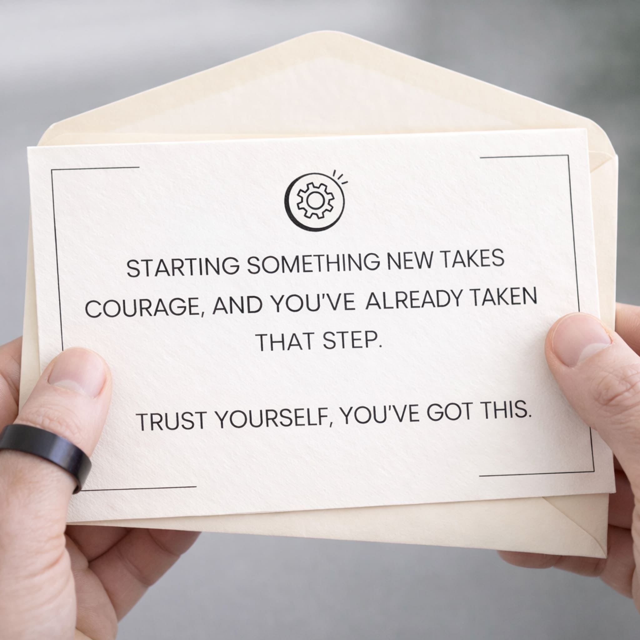 Enveloped card with motivational message held by hands against a neutral background